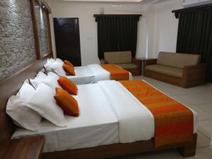 a hotel room with two beds and a chair at HISHAM SUITES in Ernakulam