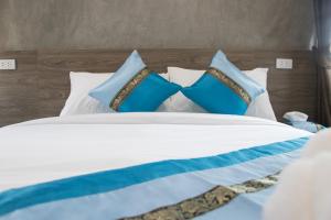 Una cama con almohadas azules y blancas. en Puak Taem Boutique Hotel en Chiang Mai