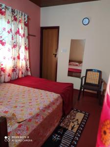 a bedroom with a bed and a chair and a mirror at VANASIRI COTTAGE (Tourist Home) in Dharmastala