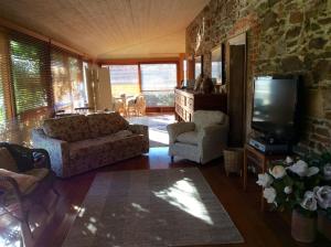 a living room with a couch and chairs and a television at The Coach House on River and Park in Mudgee +14 photos