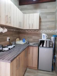 cocina con armarios de madera, fregadero y nevera en Walvis Bay Backpackers & Self-catering en Walvis Bay