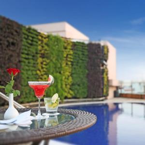 uma bebida numa mesa ao lado de uma piscina em Golden Tulip Jaipur em Jaipur