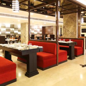 a dining room with red chairs and a table at Golden Tulip Jaipur in Jaipur