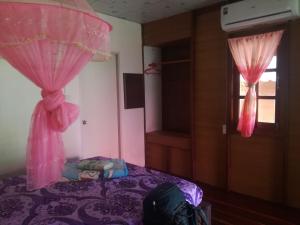 a bedroom with a bed with pink curtains and a window at Mr Bao Homestay & Bungalows in Ko Yao Noi +37 photos