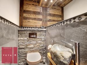 La salle de bains est pourvue de toilettes et d'un mur en pierre. dans l'établissement Erika 012, à Verbier