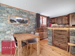cocina con mesa de madera y pared de piedra en Erika 012 en Verbier