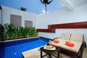 La Flora Resort Patong - SHA Extra Plus في شاطيء باتونغ: غرفة معيشة مع مسبح وأريكة وطاولة
