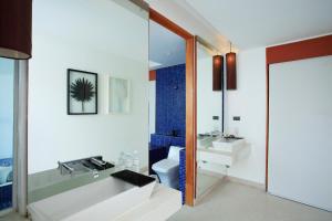 a bathroom with a tub and a sink and a toilet at La Flora Resort Patong in Patong Beach