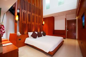 
a bedroom with a bed and a dresser at La Flora Resort Patong - SHA Extra Plus in Patong Beach
