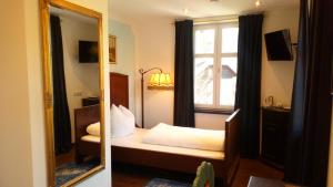 a mirror in a bedroom with a bed and a window at Die schlafende Goass - Pub und Gästehaus in Bischofswiesen