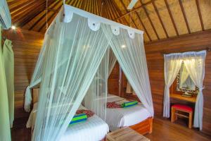 a bedroom with two beds in a wooden house at Garden Cottage Lembongan & Hostel in Nusa Lembongan