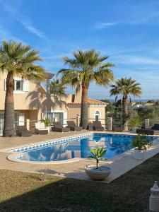 - une piscine en face d'une maison avec des palmiers dans l'établissement VILLA L'ESTAQUE, à Armação de Pêra