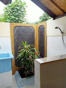a bathroom with a stone wall with a plant at Bamboo Bali in Amed