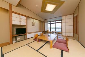 een woonkamer met een tafel en stoelen en een televisie bij Hotel Urashima in Katsuura