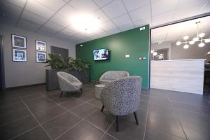 une salle d'attente avec des chaises et un mur vert dans l'établissement Hôtel Fontaine Argent - Centre Ville, à Besançon