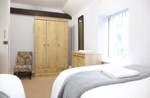 a white bedroom with a bed and a chair at The Coach House in Stamford