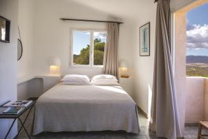 a white bedroom with a bed and a window at Résidence Les Toits de Santa Giulia in Porto-Vecchio