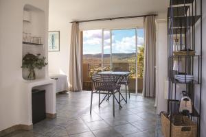 una sala da pranzo con tavolo e sedie e un balcone di Résidence Les Toits de Santa Giulia a Porto Vecchio