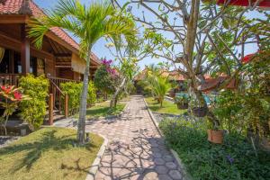 a walkway in front of a house with trees at Garden Cottage Lembongan & Hostel in Nusa Lembongan