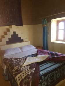 a bedroom with a bed with a cheetah blanket and a window at Family Moroccan House in Merzouga