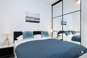 a bedroom with two beds with blue pillows at Jantar Apartamenty - Nadmorskie Tarasy SPA in Kołobrzeg