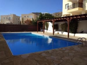 een zwembad met een pergola naast een gebouw bij Panoramic Eden in Paphos City