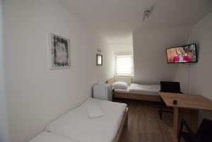 Habitación con cama, escritorio y TV en la pared. en AB Möhringen Messe Zimmer en Stuttgart