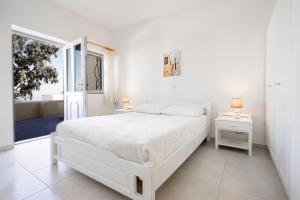 a white bedroom with a white bed and a window at Ersi Villas in Firostefani