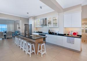 a kitchen with white cabinets and a island with bar stools at Howela Beach House in Ballito