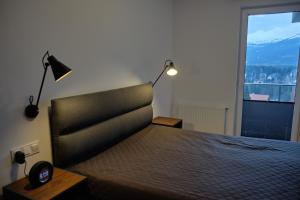 ein Schlafzimmer mit einem Bett mit zwei Lampen und einem Fenster in der Unterkunft Panorama800 - Apartamenty Cameo Szklarska Poręba in Szklarska Poręba