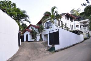 a white house with a gate on the side of a street at Antique Tourists Lodge in Kandy