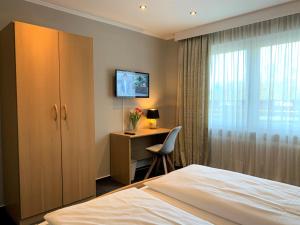 Schlafzimmer mit einem Bett, einem Schreibtisch und einem Fenster in der Unterkunft Hotel-Restaurant Fuchs in Handeloh