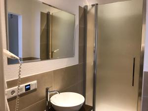 a bathroom with a sink and a shower with a mirror at Hotel-Restaurant Fuchs in Handeloh