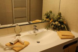 a bathroom sink with a hairbrush and a mirror at Airporthotel Salzburg - Hotel am Salzburg Airport in Salzburg