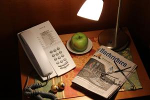 a table with a phone and an apple and a book at Airporthotel Salzburg - Hotel am Salzburg Airport in Salzburg