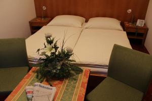 a bedroom with a bed with a table and two chairs at Airporthotel Salzburg - Hotel am Salzburg Airport in Salzburg