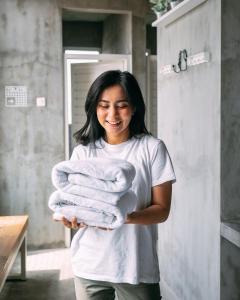 a woman is holding a stack of towels at SO! Boutique Hostel in Malang