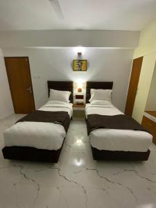 two beds in a room with marble floors at Utsavam Hotel Apartments in Guruvāyūr