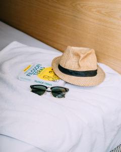um chapéu e óculos de sol em cima de uma cama em SO! Boutique Hostel em Malang