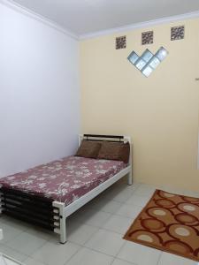 ein Schlafzimmer mit einem Bett in einem weißen Zimmer in der Unterkunft Hostel TARUNA in Genteng-kulon