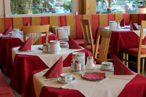 a row of tables with red napkins and cups on them at Airporthotel Salzburg - Hotel am Salzburg Airport in Salzburg