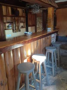 a wooden bar with three stools at a counter at Apartma Miša in Prevalje