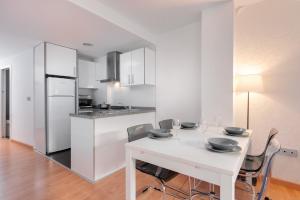 a white kitchen with a white table and chairs at Apartamentos Globus by Be Alicante in Alicante