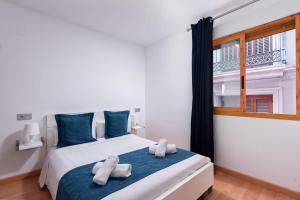 a bedroom with a bed with blue pillows and a window at Apartamentos Globus by Be Alicante in Alicante