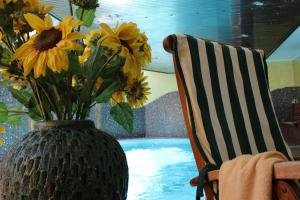a vase filled with yellow flowers next to a chair at Airporthotel Salzburg - Hotel am Salzburg Airport in Salzburg