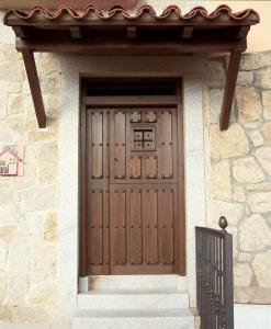 a wooden door on a stone building with a gate at EL MESÓN DE GREDOS in Navarredonda de Gredos