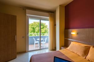 een slaapkamer met een bed en een balkon met een tafel bij Hotel Palace Magnolia SPA in Tortoreto Lido