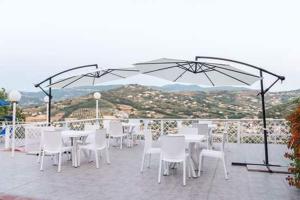a group of white tables and chairs under an umbrella at Villa Milena Apartments & Rooms in Agropoli