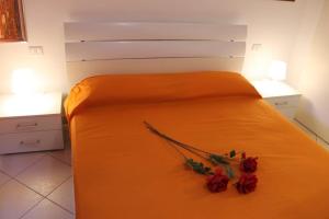 Una cama con sábanas naranjas y flores rojas. en Mono Eraclito, en Marina di Pescoluse