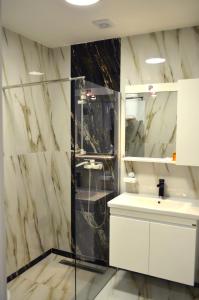 biała łazienka z prysznicem i umywalką w obiekcie Tomce Sofka Apartments w mieście Skopje